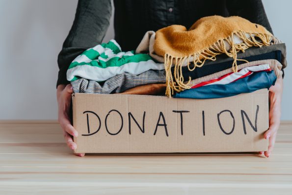 a box with the word donation written on it overflowing with clothes and various items being donated